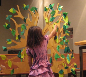 A child hangs Noahs symbol, the ark, on the Jesse Tree.