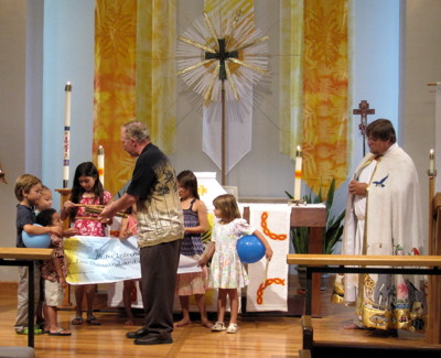 Pastor Steve Jensen presents gifts of African flutes to children who participated in the Heifer Benefit Concert.