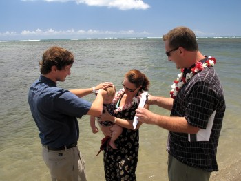 Intern Pastor Josh baptizes DJ, held by his mother and assisted by his father