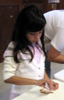 A child decorates her cookie.