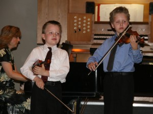 Two young violinists, accompanied by their mother