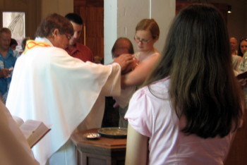 Pastor Jeff marks the newly baptized with the sign of the cross as the confirmand looks on.