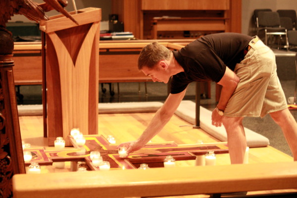 A member of the congregation places a candle as part of the Adoration of the Crucified