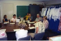 Adult Christian Education class meeting in the Board Room, amid choir robes, office equipment, and other items in storage.