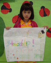 Sophie Cheng displays her poster, 'sharing and giving--stewardship! to achieve our goal.'
