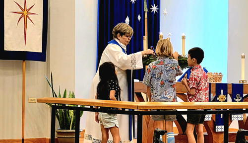 Little hands and growing faith as Pr. Lesley guides the children in adding nativity figures during the Children’s Conversation.