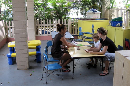 Children and nursery attendants playing on the covered lanai