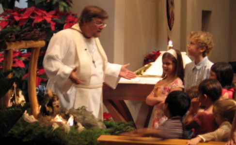 Pastor Lilley recounts the joyful Christmas story to children at the crèche.