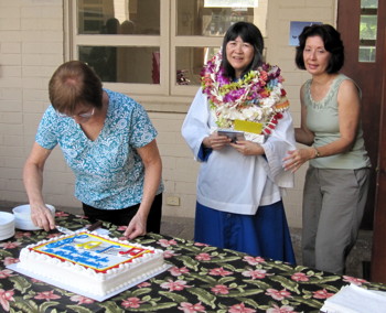 Jeanne Castello guides Kathy to the table as Mary-Jo Estes cuts the cake in her honor.