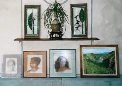 Stained glass and a bonsai plant displayed with pastel/pencil portraits and an oil landscape